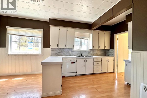 Living room with light wood laminate flooring, beige paneled walls, and large windows with a rural view. - 233 Hilldale Road, New Denmark