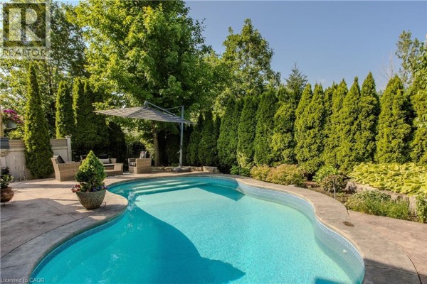 Close-up view of a swimming pool with steps, concrete patio, and outdoor seating. - 2330 Valleyridge Drive, Oakville