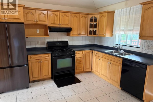 L-shaped kitchen with light wood cabinets, black appliances, dark countertops, and tile flooring. - 2337 Askin, Windsor