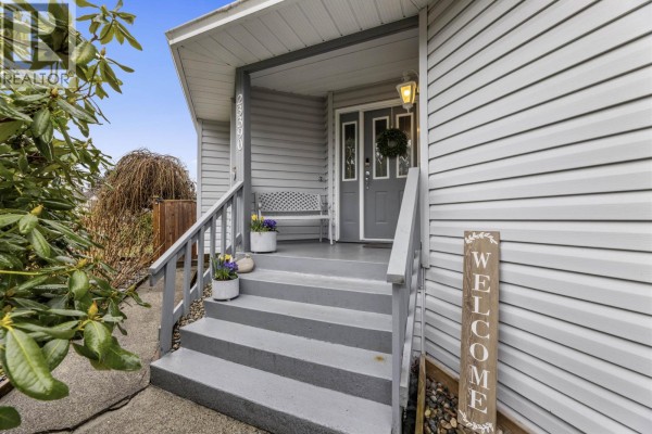 Front entrance with steps, welcome sign, and decorative plants - 23390 123 Avenue, Maple Ridge