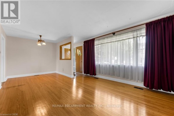 Empty dining area with hardwood floors, cream walls, a decorative mirror, and a chandelier. - 234 Pine Cove Road, Burlington