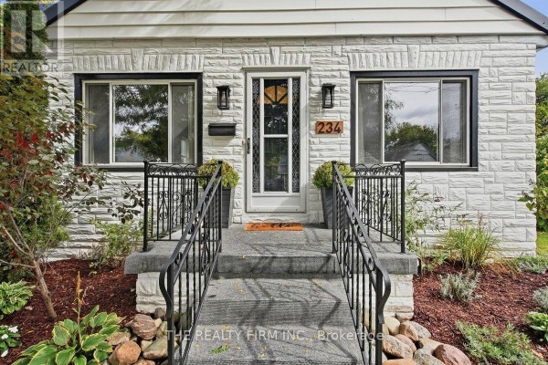Detailed view of the front door, windows, and stone steps of the white brick bungalow. - 234 St Julien Street, London East