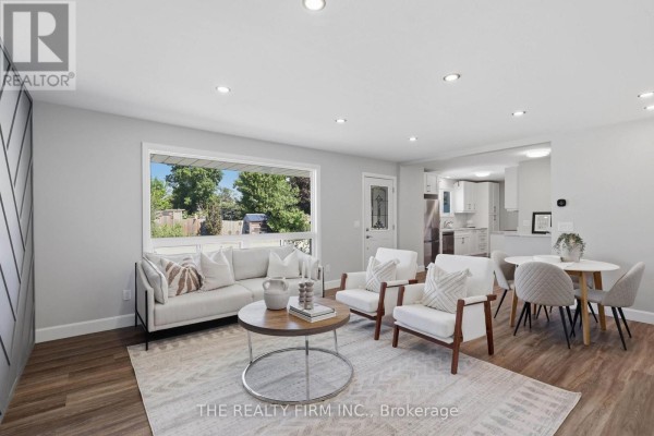 Living room with white sofa, two armchairs, coffee table, and dining set, overlooking a green backyard. - 234 West Street, Central Elgin
