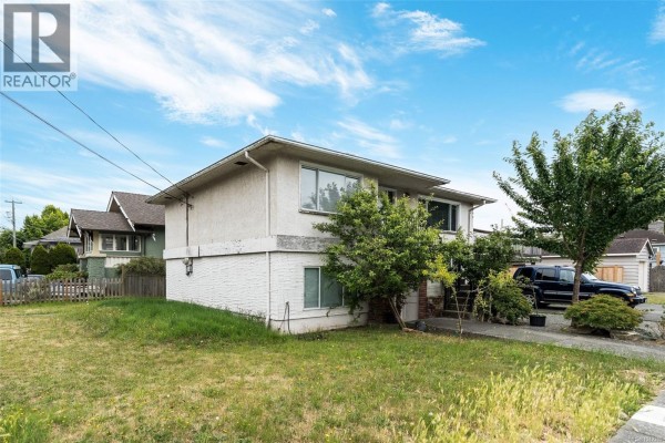 Exterior side view of the duplex with a white stucco finish and green lawn. - 2343 Shelbourne St, Victoria