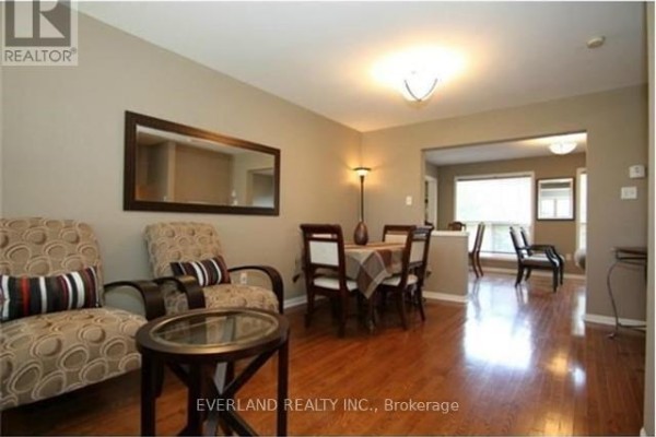 Dining room with wooden table and chairs, two patterned armchairs, and a large mirror. - 2344 Proudfoot Trail, Oakville