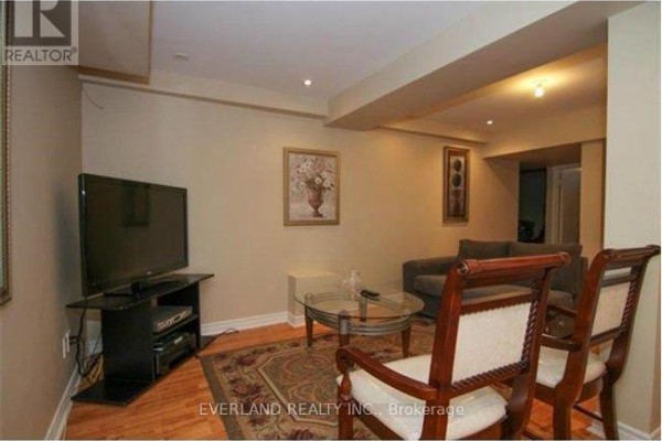 Living room with a television, sofa, coffee table, and chairs on an area rug. - 2344 Proudfoot Trail, Oakville