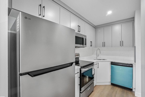 Rear exterior view of townhouse with double glass doors opening to a wooden deck. - 2345 139 Av Nw, Edmonton