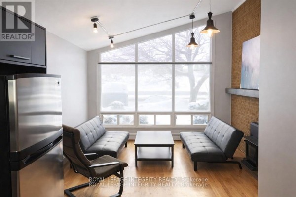 Modern kitchen with dark cabinets, stainless steel appliances, and island with stools. - 2347 Baseline Road, Ottawa