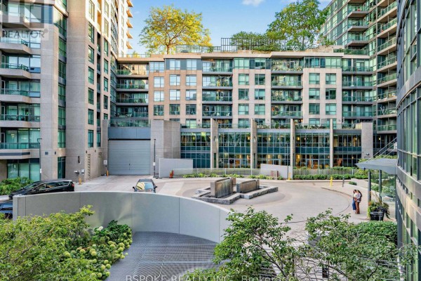 Courtyard view of a modern condo building with glass balconies and landscaping. - 235 - 231 Fort York Boulevard, Toronto