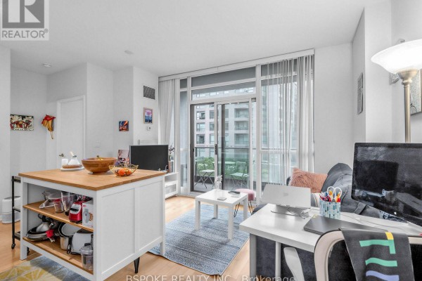 Living room with a sofa, coffee table, and a kitchen island with stools. - 235 - 231 Fort York Boulevard, Toronto