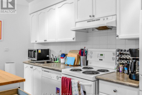 Close-up view of a white kitchen with a stovetop, microwave, and cabinets. - 235 - 231 Fort York Boulevard, Toronto