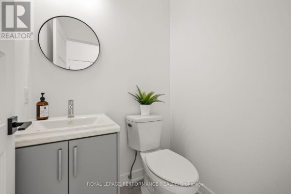 Powder room with round mirror, modern vanity, and toilet - 235 Bourdeau Boulevard The Nation