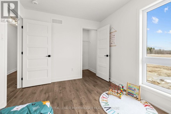 Modern bedroom with wood-look floor, walk-in closet, and toys - 235 Bourdeau Boulevard The Nation