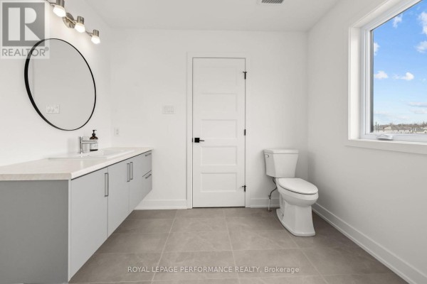 Modern bathroom with floating vanity, round mirror, and toilet - 235 Bourdeau Boulevard The Nation