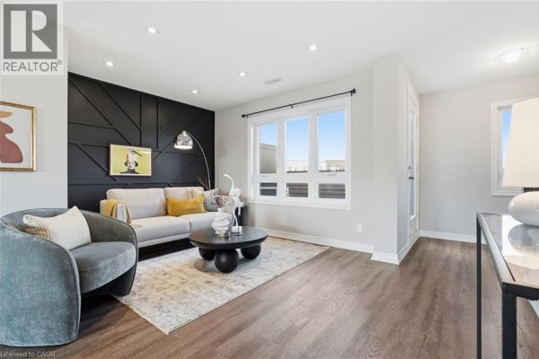 Living room with grey armchair, sofa, black coffee table, and large window. - 235 Chapel Hill Drive Unit# 31, Kitchener