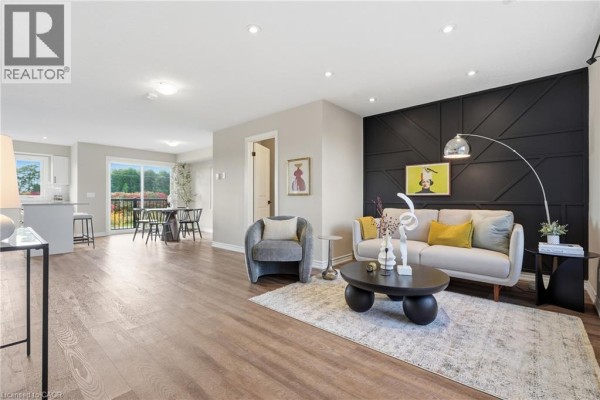 Open concept living and dining area with balcony access and dark accent wall. - 235 Chapel Hill Drive Unit# 31, Kitchener