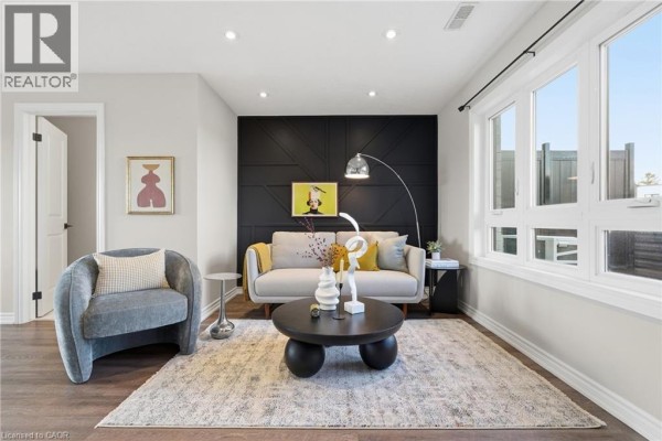 Living room featuring a sofa, armchair, coffee table, and decorative wall panel. - 235 Chapel Hill Drive Unit# 31, Kitchener