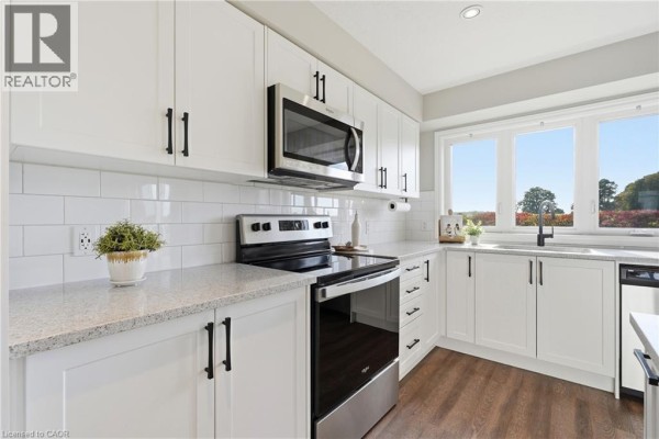 White kitchen with granite countertops, stainless steel appliances, and subway tile backsplash. - 235 Chapel Hill Drive Unit# 31, Kitchener