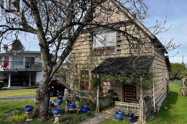 Front entrance of the house with a small porch, surrounded by bare tree branches and blue decorative pots. - 235 Durham Street, New Westminster