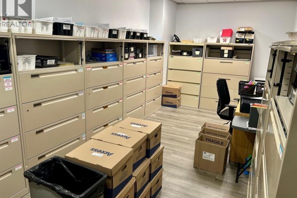 A room filled with filing cabinets, storage shelves, boxes, and a desk with an office chair. - 235 Eugenie Street West Unit# 208, Windsor