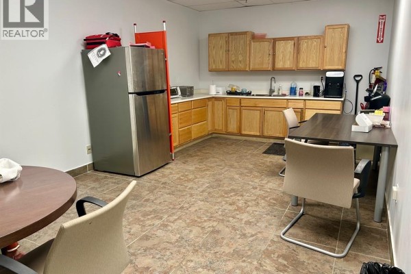A kitchenette area with a refrigerator, cabinets, sink, microwave, and a dining table with chairs. - 235 Eugenie Street West Unit# 208, Windsor