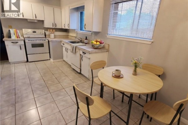 Kitchen with white cabinets, a white stove, a dishwasher, and a small dining table with chairs. - 235 Wilson Road N Unit# 1, Oshawa