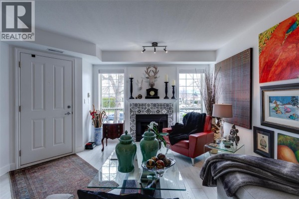 Entrance to the living room featuring a white door, fireplace, and furniture. - 2350 Stillingfleet Road Unit# 113, Kelowna