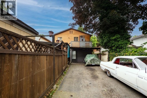 Backyard alley with a wooden fence, covered carport, and a classic white car. - 2351 Hawthorne Avenue, Port Coquitlam