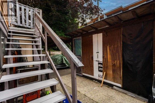 Outdoor wooden stairs leading down next to a wooden shed with a tarped window. - 2351 Hawthorne Avenue, Port Coquitlam