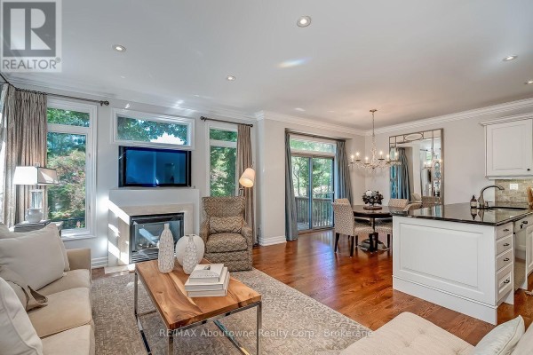 Open concept living and dining area with a fireplace, dark granite island, and a chandelier. - 2351 Woodfield Road, Oakville