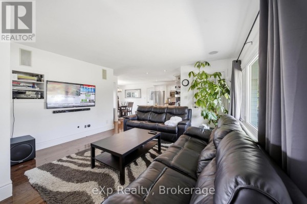 Living room with black leather sofas, a black coffee table, zebra print rug, and mounted TV. - 2352 County Road 3, Prince Edward County