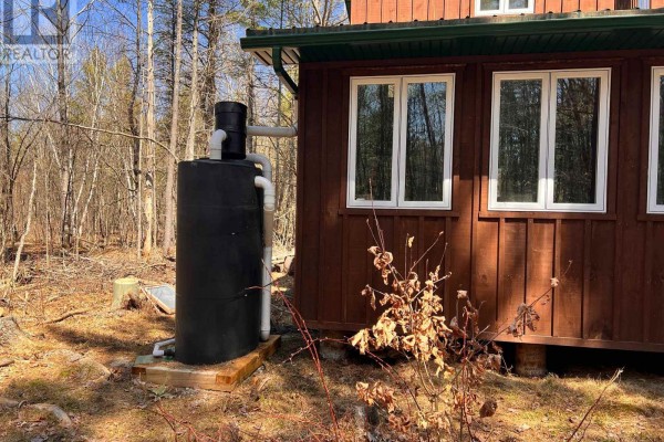Water storage tank connected to the side of the rustic wooden cabin. - 2355 Raymo Road, Frontenac