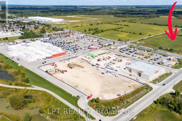 Red arrow indicates a green field next to a construction site and a large retail shopping plaza. - 2359 Glenwoods Avenue, Georgina