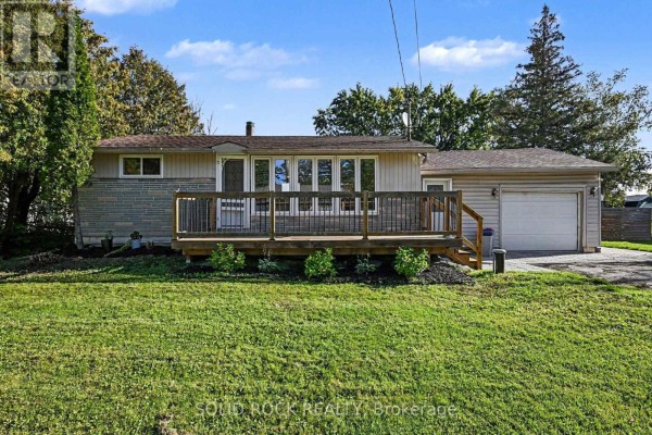 Front exterior of a single-story house with a wooden deck and attached garage under a blue sky. - 236 Campbell Drive N, Mcnab/braeside