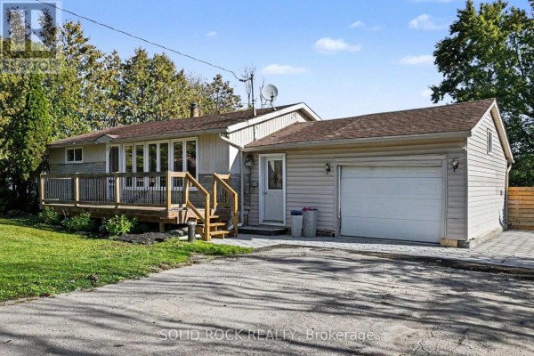 Side and front view of a house with a wooden deck, attached garage, and paved driveway. - 236 Campbell Drive N, Mcnab/braeside