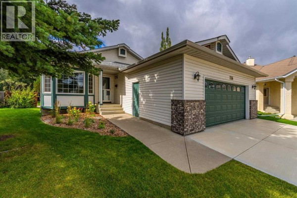 Side exterior view of a beige house with a dark green garage door and attached single garage. - 236 Edgebrook Gardens Nw, Calgary