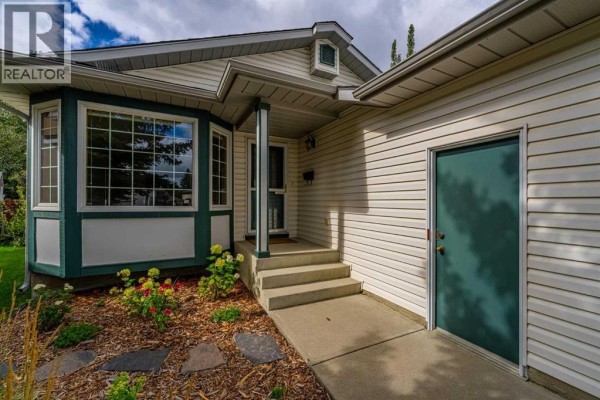 Close-up of the house entrance with steps, a bay window, and a teal door. - 236 Edgebrook Gardens Nw, Calgary