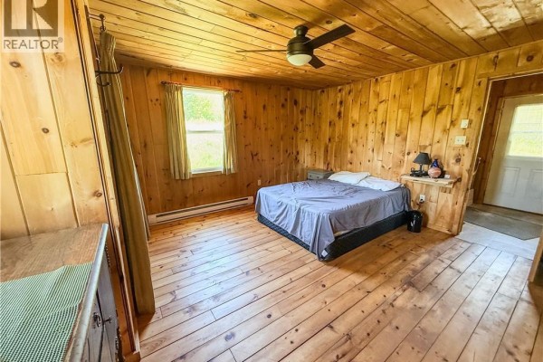 Aerial view of two small buildings in a clearing surrounded by dense forest and a pond. - 236 Mill Brook Road, Mill Brook