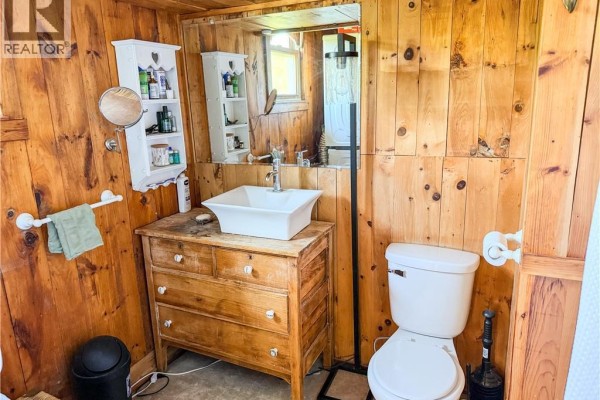 Exterior of a log cabin with a red metal roof, surrounded by a large green meadow and rolling hills. - 236 Mill Brook Road, Mill Brook