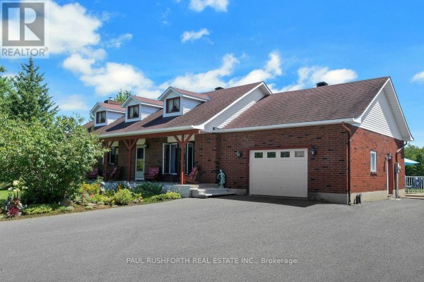 Aerial view of a ranch-style house surrounded by mature trees and open fields. - 2362 Russland Road, Russell
