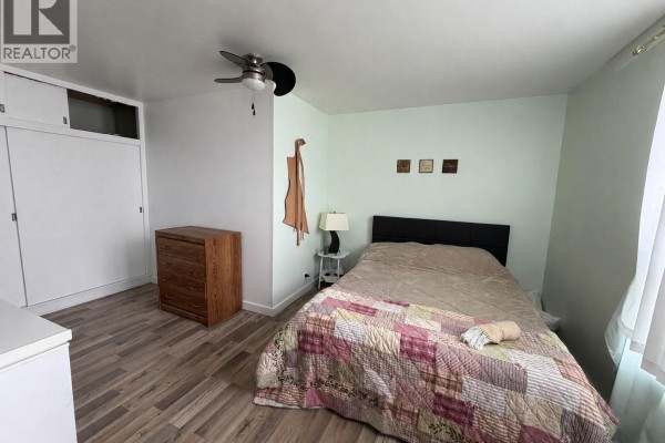 Bedroom with a bed, wooden dresser, white closet, and a ceiling fan. - 2364 Proton Avenue, Gull Lake