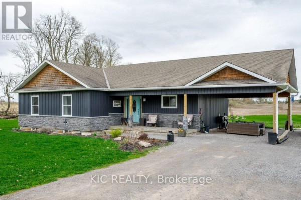 Exterior of a bungalow featuring dark siding, stone accents, and a covered parking area. - 2366 Asphodel 10th Line, Asphodel Norwood