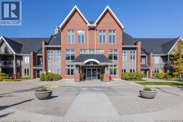 Apartment building entrance with a red brick facade, gray siding, and a covered walkway. - 237, 15 Everstone Drive Sw, Calgary