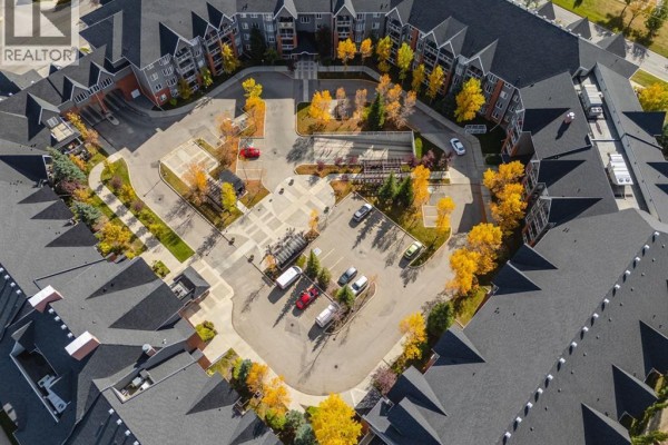 Aerial view of apartment complex with U-shaped driveway, parking, and autumn foliage. - 237, 15 Everstone Drive Sw, Calgary