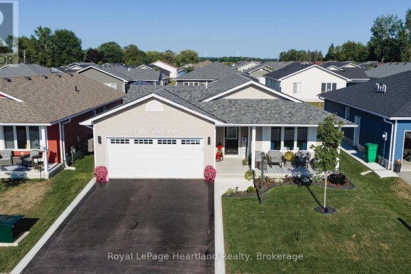 Exterior view of a beige bungalow with a green lawn and adjacent houses. - 237 Lake Breeze Drive, Ashfield Colborne Wawanosh