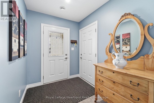 Interior entryway with blue walls, white doors, a patterned rug, and a wooden dresser. - 237 Lake Breeze Drive, Ashfield Colborne Wawanosh
