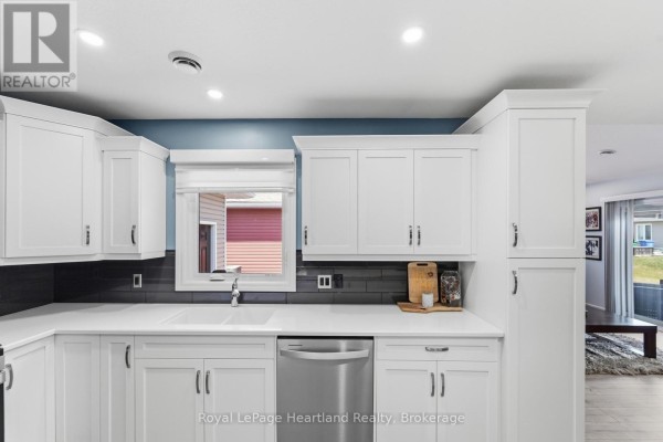 Close-up of white kitchen cabinets, a quartz countertop, and a dark subway tile backsplash. - 237 Lake Breeze Drive, Ashfield Colborne Wawanosh