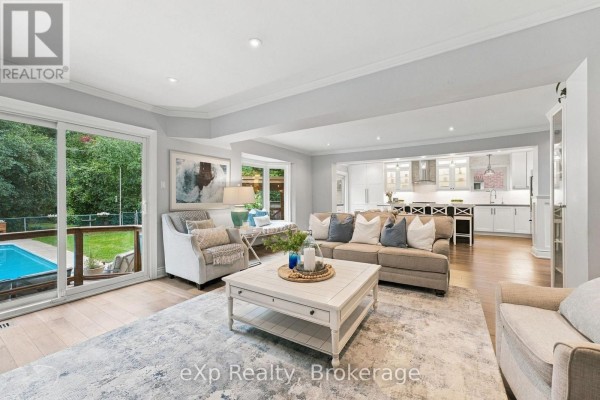 Living room with sectional sofa, fireplace, and view of backyard pool and kitchen. - 237 Lake Driveway W, Ajax