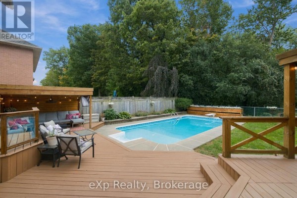 Backyard with an in-ground pool, wooden deck, covered patio, and wooden fence. - 237 Lake Driveway W, Ajax