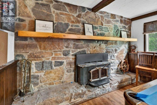 Stone fireplace with wood stove and beam ceiling - 237 Old River Road Leeds And The Thousand Islands